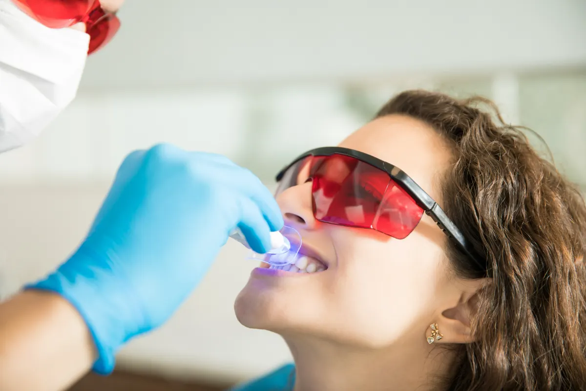 Paciente recebendo clareamento dental com luz em consultório